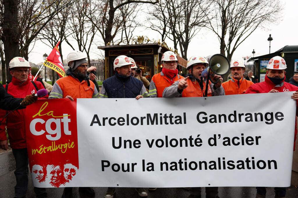 Des employés du sidérurgiste ArcelorMittal brandissent une banderole du syndicat CGT Métallurgie sur laquelle on peut lire « ArcelorMittal Gandrange. Une volonté de fer pour la nationalisation » lors d'une manifestation près de l'Assemblée nationale, où les députés examineront un projet de loi proposé par le parti politique LFI visant à nationaliser les sites du groupe sidérurgique ArcelorMittal, à Paris, le 27 novembre 2025.