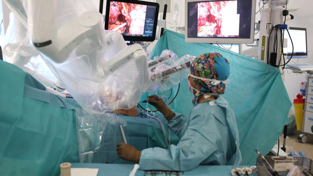 Uma enfermeira auxilia o cirurgião Sylvain Ducrocq durante uma cistectomia radical com o robô cirúrgico Da Vinci no Hospital de Ajaccio, na ilha mediterrânea francesa da Córsega, em 3 de abril de 2025.