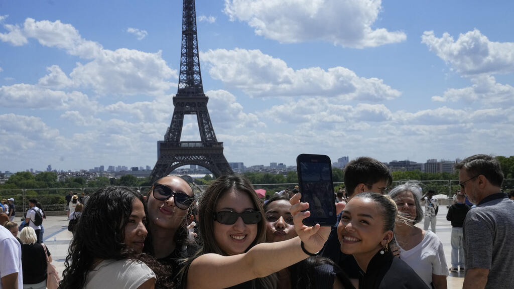FILE - Tourists pose for a selfie with the Eiffel Tower in background, Thursday, July 6, 2023 in Paris. (AP Photo/Michel Euler, File)