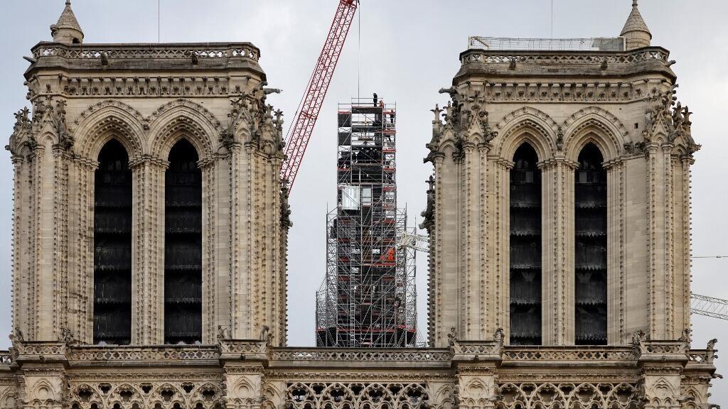 Les ouvriers placent la croix au sommet de la flèche nouvellement reconstruite, lors des travaux de reconstruction, à la cathédrale Notre-Dame de Paris, le 6 décembre 2023. 