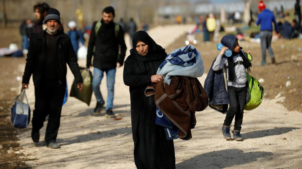 Les migrants marchent vers la frontière alors qu'ils se heurtent à la police anti-émeute grecque au poste-frontière turc de Pazarkule avec la Grèce Kastanies, près d'Edirne, le 6 mars 2020.