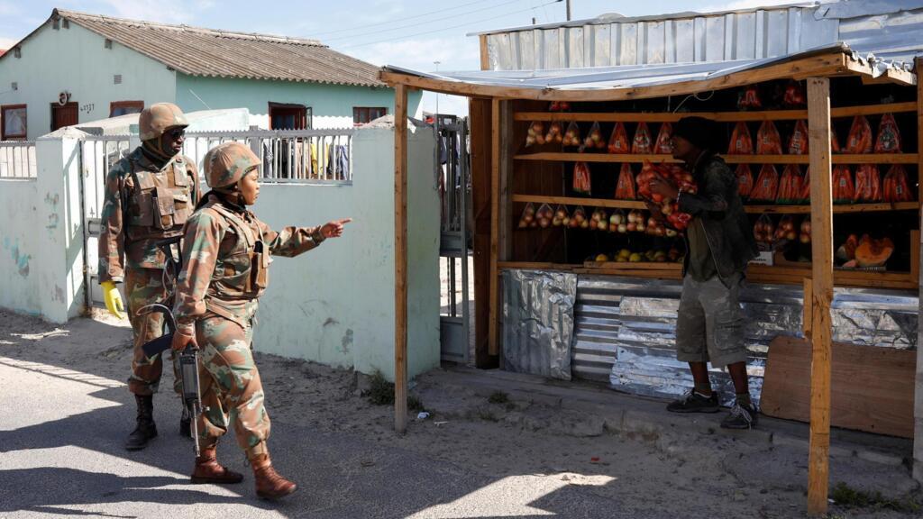 Un soldat demande à un vendeur de fermer sa boutique alors que les autorités tentent de faire respecter le confinement de 21 jours visant à limiter la propagation du Covid-19, dans le canton de Khayelitsha près de Cape Town, le 27 mars 2020.