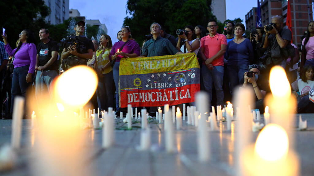Uma pessoa segura a bandeira nacional da Venezuela com a inscrição "Venezuela, livre e democrática" durante uma vigília em homenagem aos cidadãos que foram detidos após resultados eleitorais contestados, em Caracas, Venezuela, em 8 de agosto de 2024.
