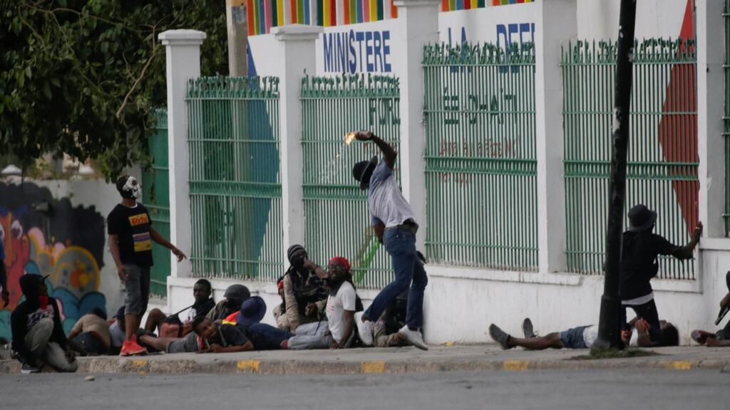 Un manifestant lance lance un cocktail molotov en direction du stand du ministère de la Défense installé sur le Champs de Mars pour le carnaval de Port-au-Prince.