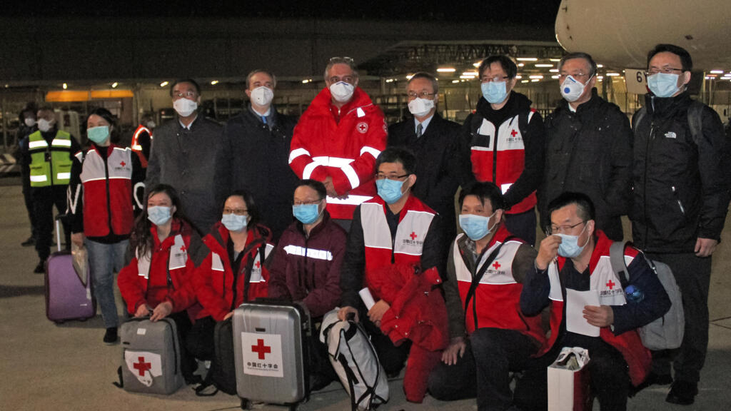 Des médecins chinois posent à leur arrivée à Rome, le mardi 13 mars 2020, alors qu'ils viennent en soutien aux médecins italiens.