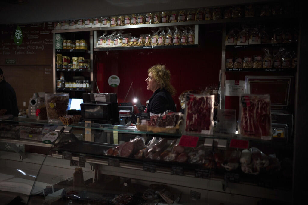 Vendedores usam a luz do celular para selecionar e registrar alimentos durante um apagão de grandes proporções em Barcelona, Espanha, na segunda-feira, 28 de abril de 2025.