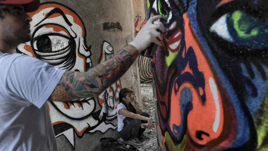 Artista urbano desenha em parede de uma fábrica abandonada em Santo André (SP), em 2010.
