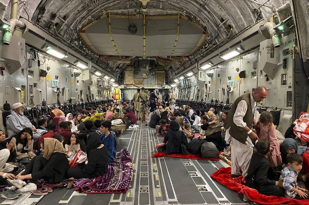 Des Afghans assis à bord d'un avion militaire américain pour quitter l'Afghanistan, à l'aéroport militaire de Kaboul, le 19 août 2021.