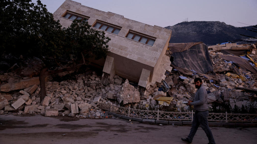 A man walks by a collapsed building and rubble, in the aftermath of a deadly earthquake, in Antakya, Hatay province, Turkey, February 21, 2023. 