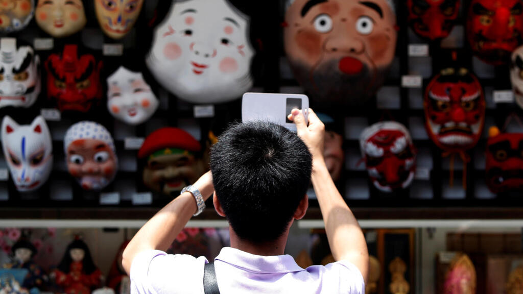 Một du khách Trung Quốc chụp ảnh mặt nạ truyền thống của Nhật Bản tại một cửa hàng lưu niệm ở quận Asakusa, Tokyo, Nhật Bản, ngày 17/07/2014.