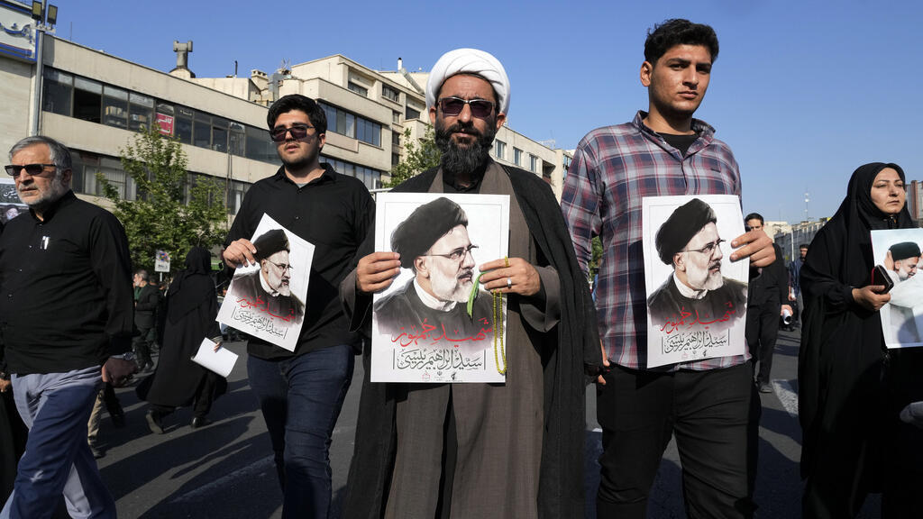 Mourners hold posters of the late Iranian President Ebrahim Raisi during a funeral ceremony for him and his companions who were killed in a helicopter crash on Sunday in a mountainous region of the country's northwest, in Tehran, Iran, Wednesday, 22 May, 2024. 