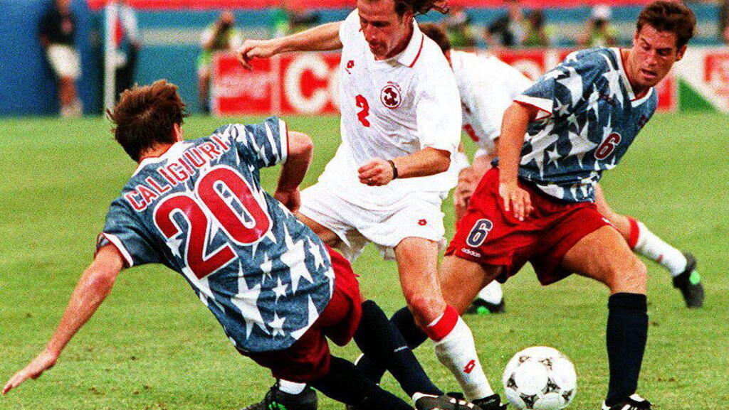 Marc Hottiger (c) de Suisse est pris en sandwich entre Paul Caligiuri (g) et John Harkes (d) des États-Unis lors de leur match de Coupe du monde de soccer au Pontiac Silverdome le 18 juin 1994.