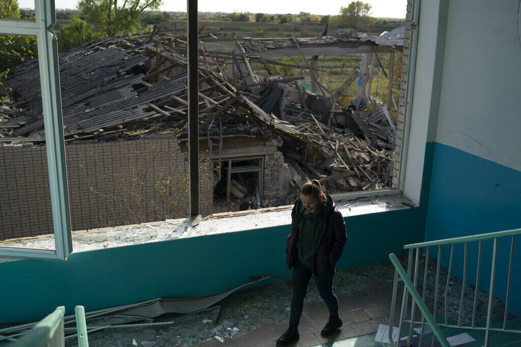 Tetyana Samarenkova desce as escadas de uma escola fortemente danificada após um ataque russo, há dois dias, no vilarejo de Velyka Kostromka, na região de Dnipropetrovsk, Ucrânia, quinta-feira, 13 de outubro de 2022.