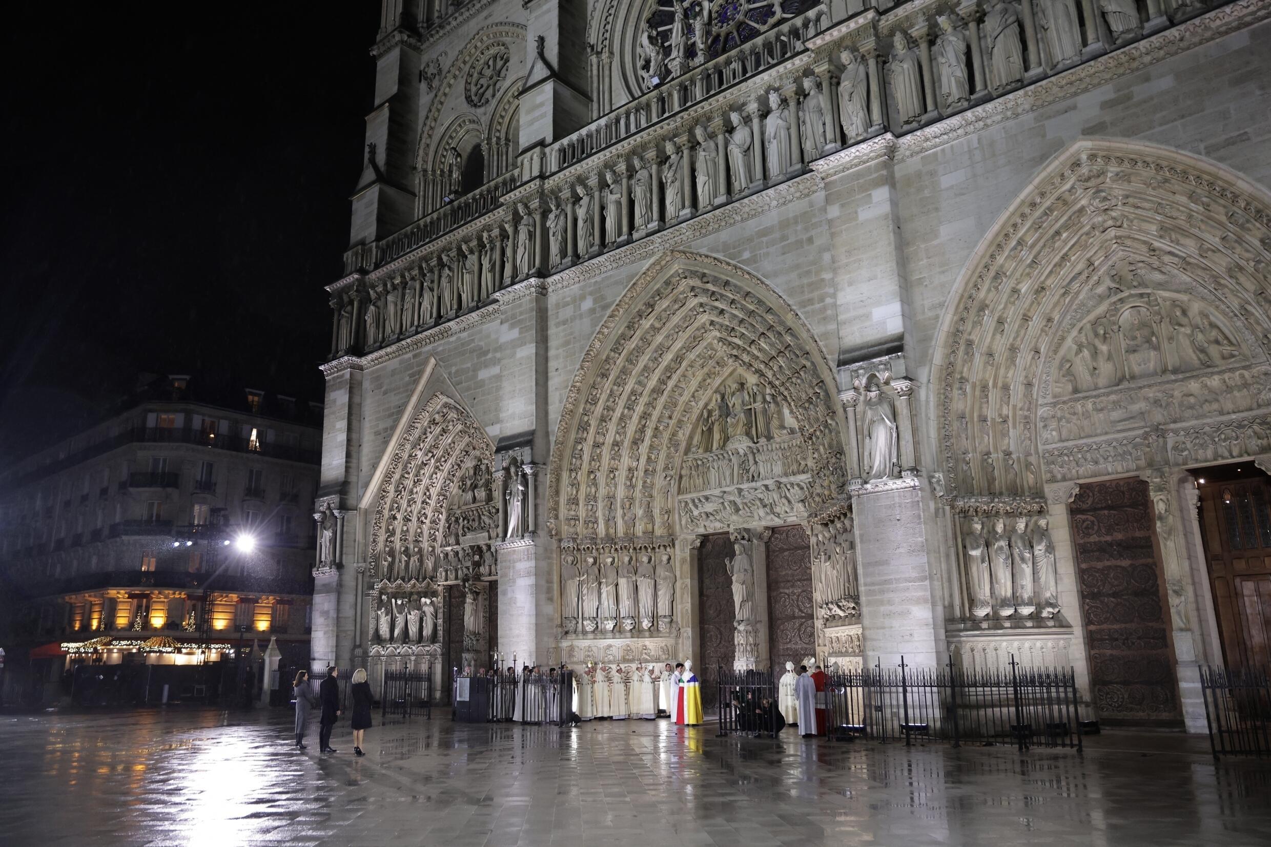 A catedral Notre-Dame de Paris é uma obra-prima gótica. Ela foi reaberta cinco anos depois do incêndio de 2019. Cerca de 250 empresas e centenas de especialistas participaram do projeto de restauração, que durou cinco anos, a um custo de € 700 milhões.  Emmanuel Macron, Brigitte Macron e a prefeita de Paris, Anne Hidalgo, diante da porta da catedral, na noite de reabertura.  Em 7 novembro de 2024. (Foto de Christophe PETIT TESSON / POOL / AFP)