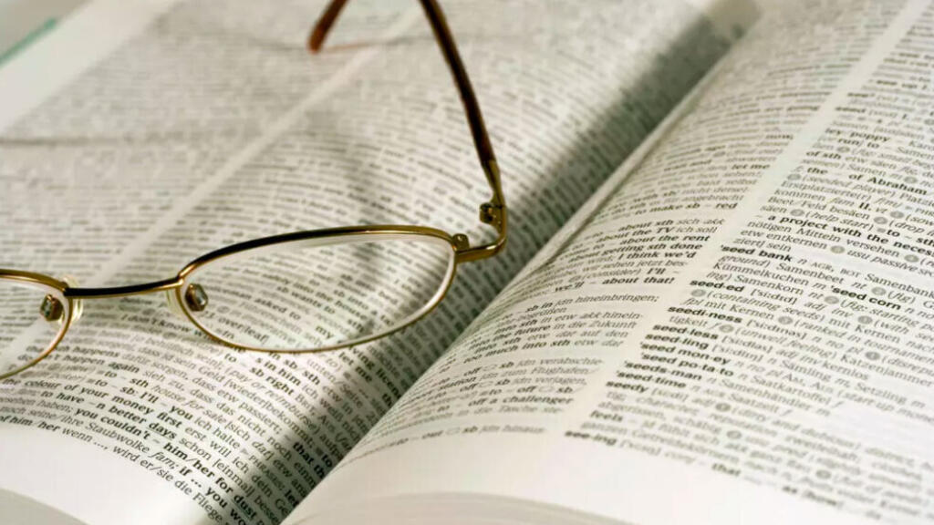 Une paire de lunettes posée sur un livre papier.