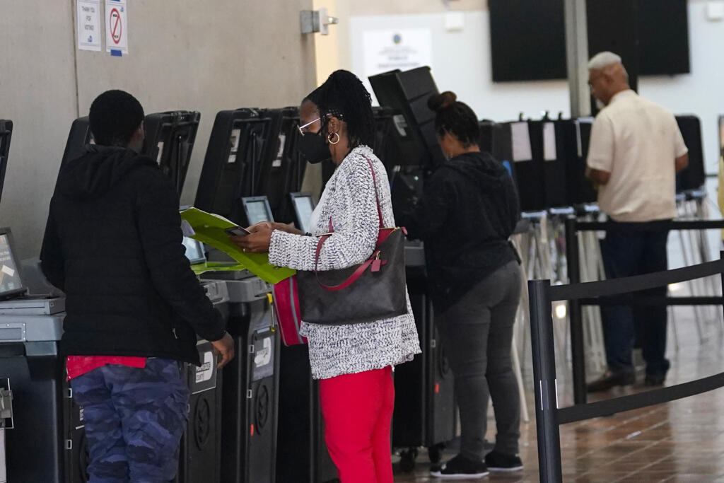 Un agent de vote dirige les électeurs vers un site de vote anticipé, le lundi 31 octobre 2022, à Miami. Les élections de mi-mandat sont le 8 novembre.