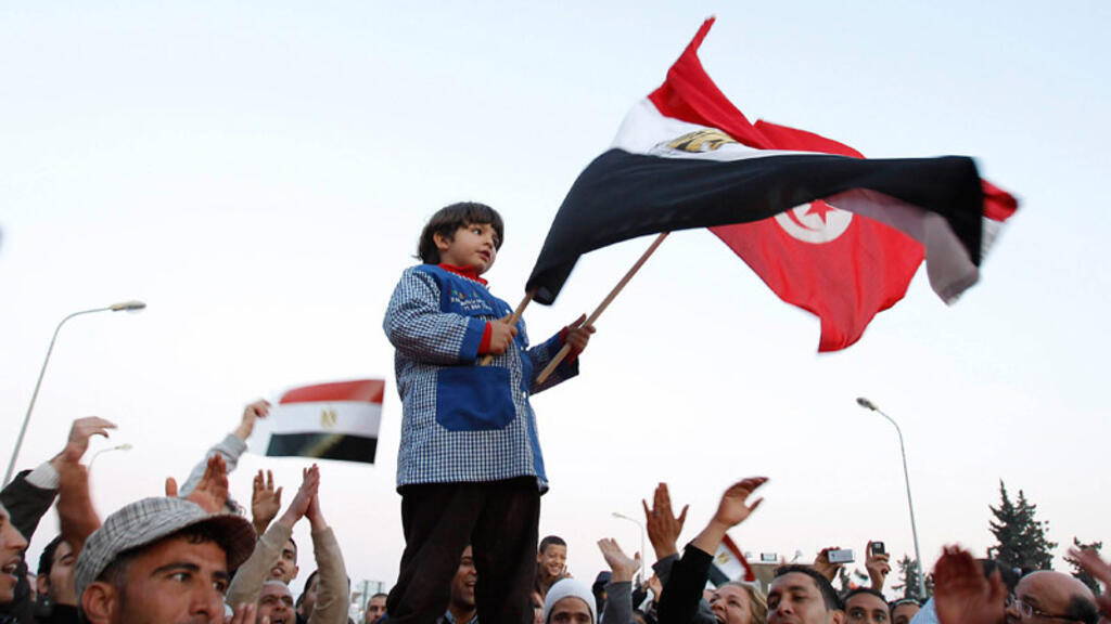 Un garçon brandit les drapeaux tunisien et égyptien, pendant la scène de joie célébrant le départ du président égyptien Hosni Moubarak, devant l'ambassade d'Egypte à Tunis, le 11 février 2011.