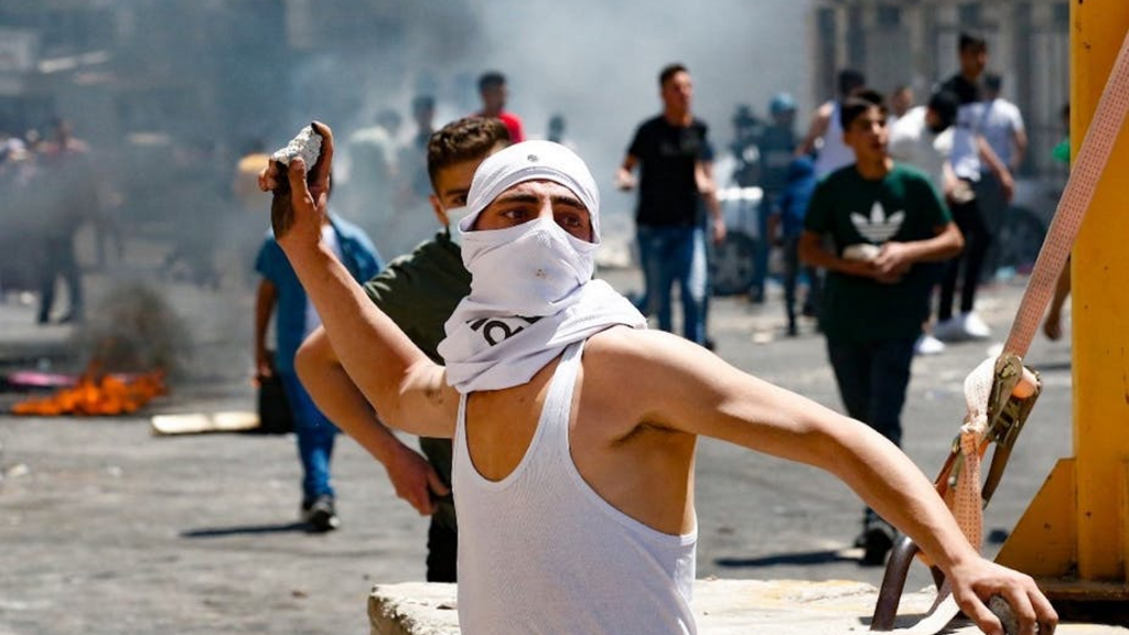 Un jeune Palestinien lance des pierres en direction des forces de sécurité israéliennes, lors d'affrontements à Hébron, en Cisjordanie, le 14 mai 2021.