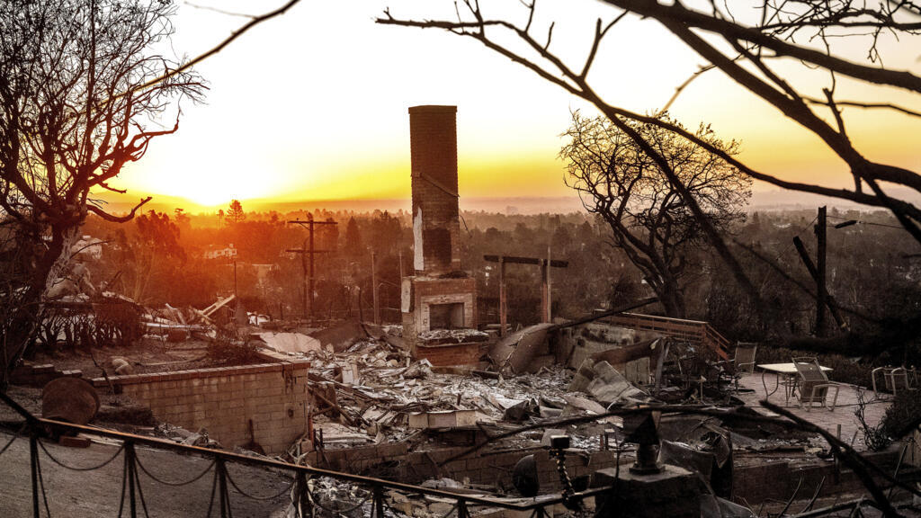 Le soleil se lève derrière une maison détruite par l'incendie de Palisades dans le quartier de Pacific Palisades à Los Angeles, le dimanche 12 janvier 2025.