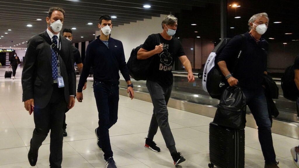 Novak Djokovic (au centre) à l’aéroport de Melbourne, avant d’embarquer sur un vol quittant l’Australie, le 16 janvier 2022.
