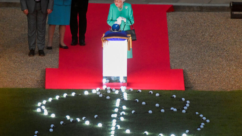 La reine Elizabeth II touche le globe des Nations du Commonwealth pour allumer le phare principal à l'extérieur du palais de Buckingham à Londres, depuis le quadrilatère du château de Windsor à Windsor, à l'ouest de Londres, le 2 juin 2022, dans le cadre des célébrations du jubilé de platine.