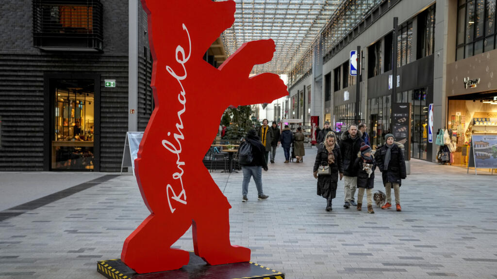 Pessoas passam por um logotipo do Festival Internacional de Cinema Berlinale em um shopping center, em Berlim, Alemanha, quarta-feira, 12 de fevereiro de 2025. (AP Photo/Ebrahim Noroozi)