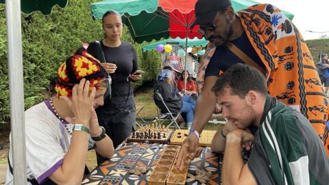 Le président du Club Awalé, Ngoufo Gangnimaze (centre de l'image), explique les règles du jeu aux festivaliers du Yardland.