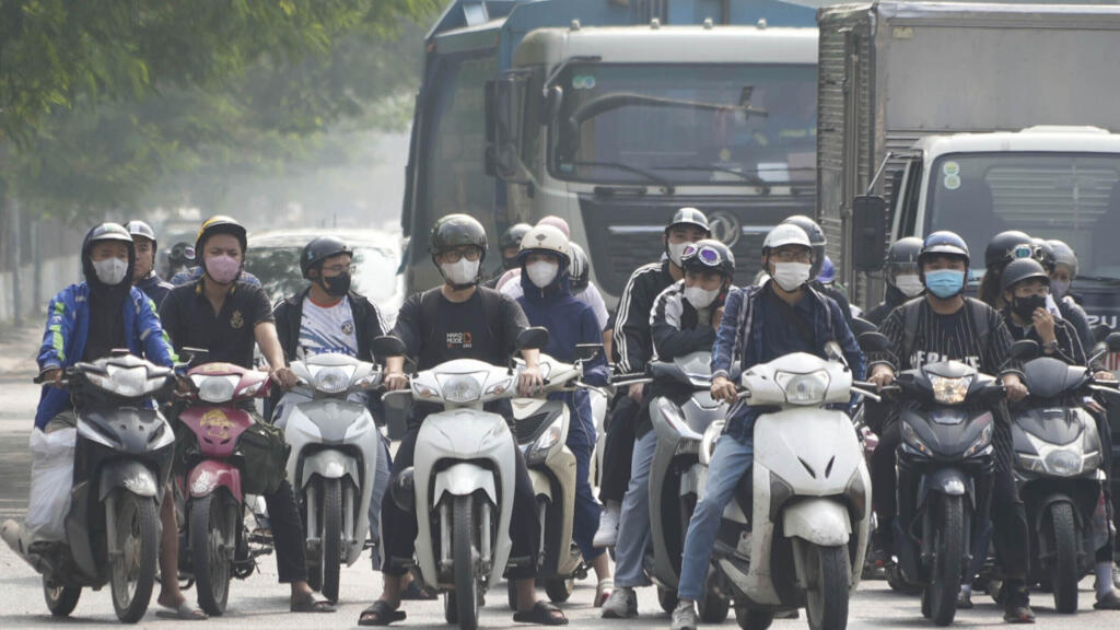 People wearing face masks wait at a traffic signal in Hanoi, Vietnam, Thursday Nov. 14, 2024. (AP Photo/Hau Dinh)