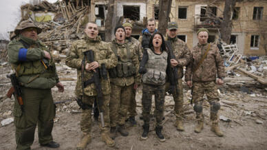 Soldados ucranianos entoam cantos patrioticos diante de prédio destruido pelas forças russas em Borodyanka (imagem de 5 abril de 2022)