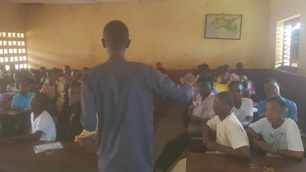Cheick Sékou Berthe, président du Club RFI Kankan dans une classe, pour expliquer l’intérêt de planter et prendre soin des arbres.