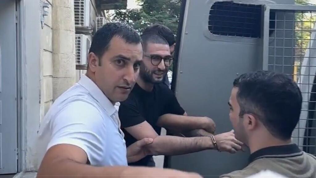 O pesquisador e pacifista Bahruz Samadov, de camisa preta, ao centro, é levado pela forças policiais no Azerbaijão.