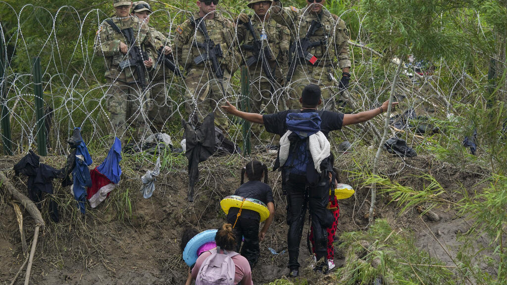 Imigrantes face a guardas nacionais do Texas na margem do rio Rio Grande, visto de Matamoros, México, quinta-feira, 11 de maio de 2023.