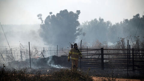 Un pompier israélien marche près de la fumée et du feu à la suite de roquettes frontalières lancées vers Israël depuis le Liban, dans le contexte des hostilités transfrontalières en cours entre le Hez