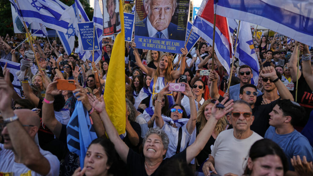 Les gens réagissent alors qu'ils se rassemblent pour regarder la retransmission en direct de la libération des otages israéliens à Gaza, sur une place connue sous le nom de « place des otages » à Tel Aviv, en Israël, le lundi 13 octobre 2025.