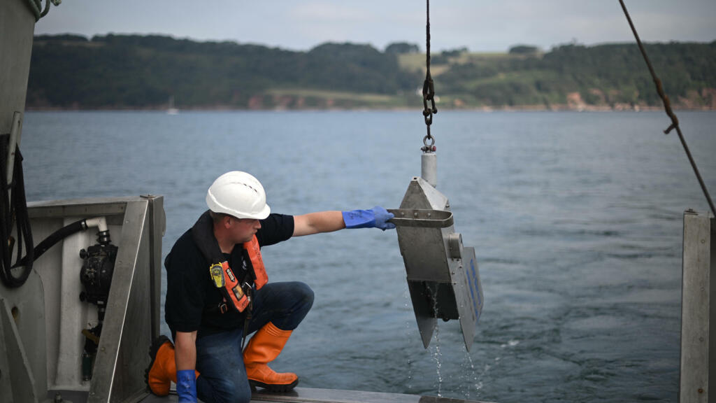 Un membre de l'équipage du navire scientifique MBA Sepia tient le dispositif d'enregistrement continu du plancton (CPR) le 26 août 2021 au large de la côte de Plymouth, dans le sud de l'Angleterre.