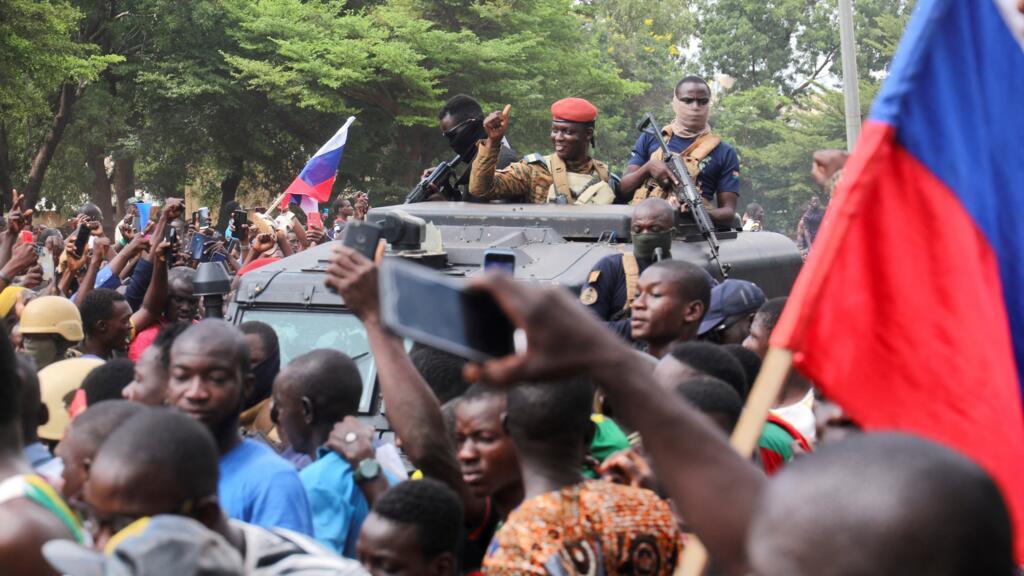 Ibrahim Traoré, est accueilli par des partisans portant des drapeaux russes alors qu'il arrive à la télévision nationale debout dans un véhicule blindé à Ouagadougou, Burkina Faso, le 2 octobre 2022.