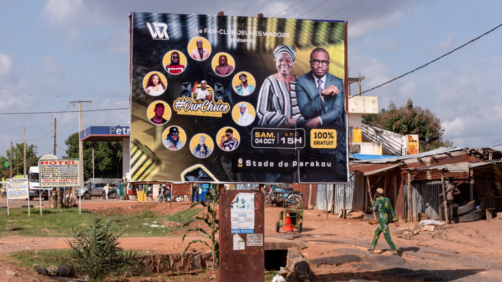 Un homme passe devant un panneau d'affichage annonçant la cérémonie d'investiture du ministre des Finances et candidat présidentiel de la coalition au pouvoir, Romuald Wadagni (premier, à partir de la droite), et de sa colistière, la vice-présidente du Bénin, Mariam Chabi Talata (seconde, à partir de la droite), à Parakou, au Bénin, le 3 octobre 2025.