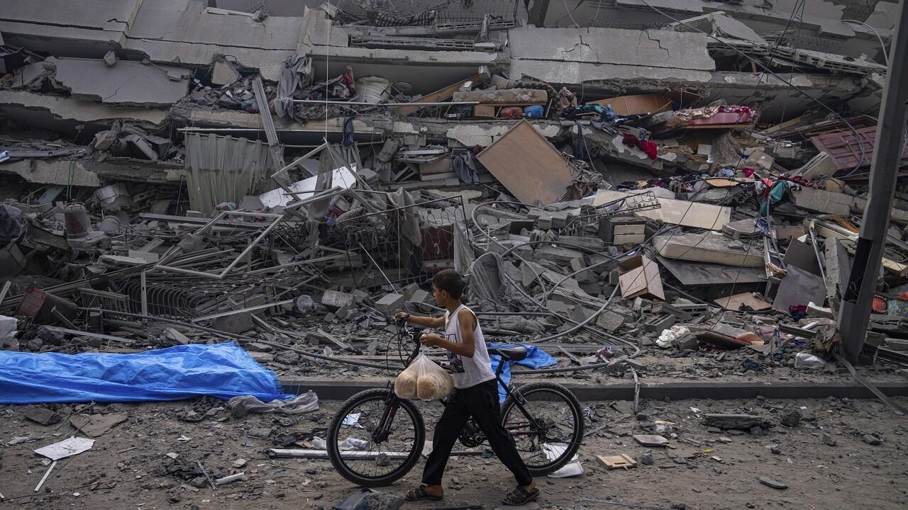 Un enfant palestinien marche en poussant sa bicyclette devant les ruines d'un immeuble détruit par une attaque aérienne de l'armée israélienne à Gaza, le 8 octobre 2023.