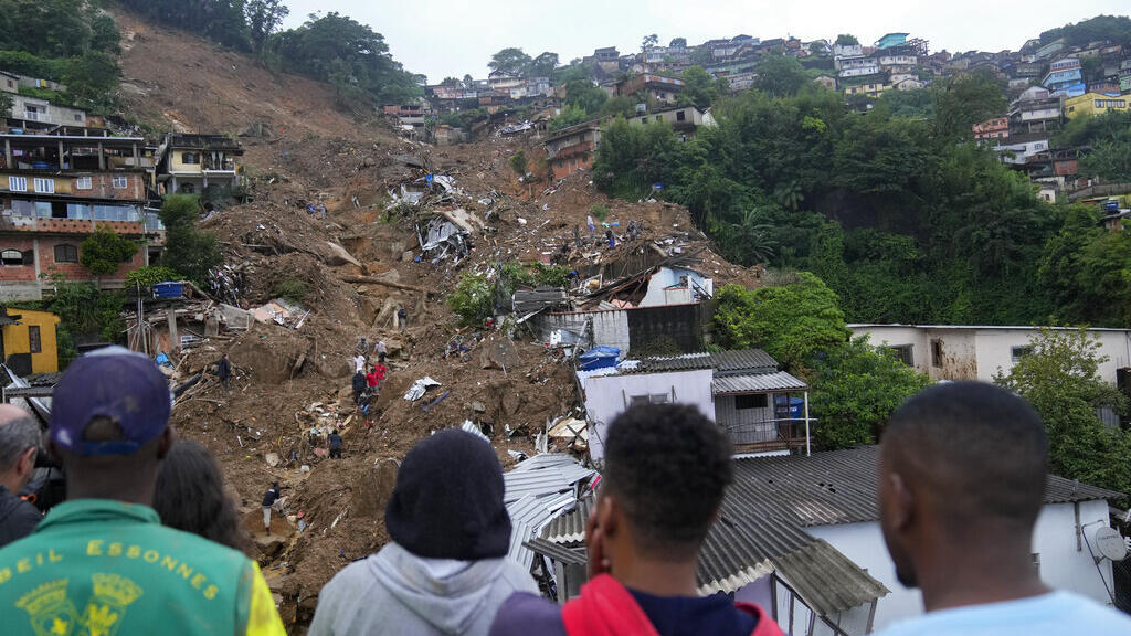 Pessoas observam deslizamento em morro ocupado irregularmente em Petrópolis (RJ), em fevereiro.