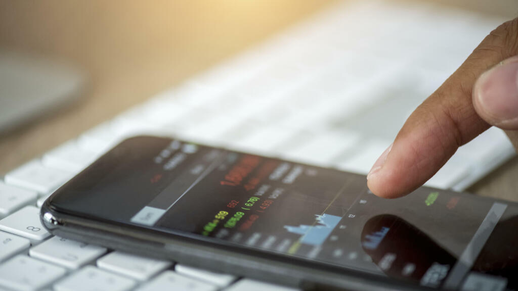 Un investisseur vérifie les données boursières par mobile. (Image d'illustration)
