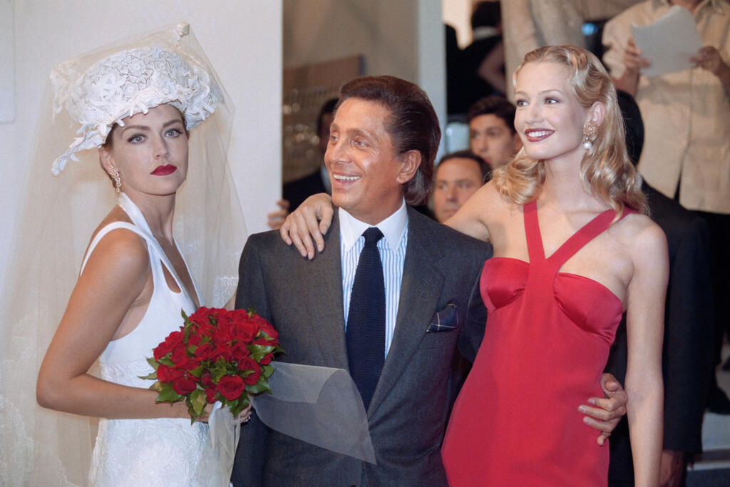 L'actrice américaine Sharon Stone (à gauche), vêtue d'une robe de mariée signée du couturier italien Valentino (au centre), et le mannequin néerlandais Karen Mulder posent à la fin du défilé de la collection printemps-été 1994 de Valentino, le 13 octobre 1993 à Paris.