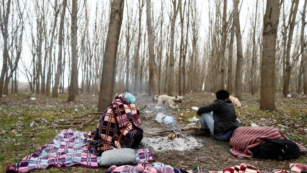 Des migrants sont assis dans un champ à la frontière turco-grecque dans le village de Doyran près d'Edirne, en Turquie, le 4 mars 2020.