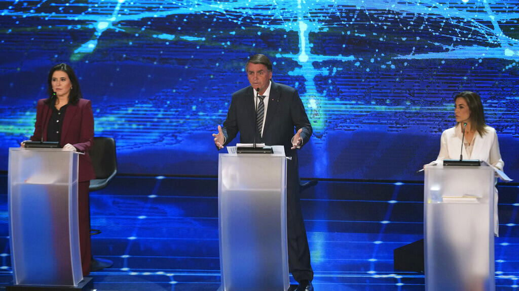 O atual presidente brasileiro Jair Bolsonaro, que tenta se reeleger, entre as candidatas Simone Tebet, do Partido do Movimento Democrático Brasileiro (esquerda) e Soraya Thronicke, do Partido União Brasil (d), no primeiro debate a presidencial em São Paulo, 28 de agosto de 2022.