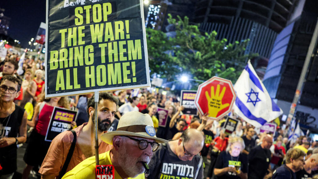 Un manifestant brandit une pancarte lors d'une manifestation organisée par les familles des otages israéliens capturés dans la bande de Gaza depuis octobre 2023, appelant à agir pour obtenir leur libération et un cessez-le-feu dans la guerre contre le Hamas, devant le siège du ministère de la Défense à Tel-Aviv, le 23 août 2025.
