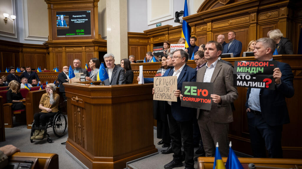 Các nghị sĩ đối lập giơ biển hiệu phản đối tham nhũng trong chính phủ của tổng thống Volodymyr Zelensky. Ảnh chụp tại Quốc Hội Ukraina, ngày 18 tháng 11 năm 2025.