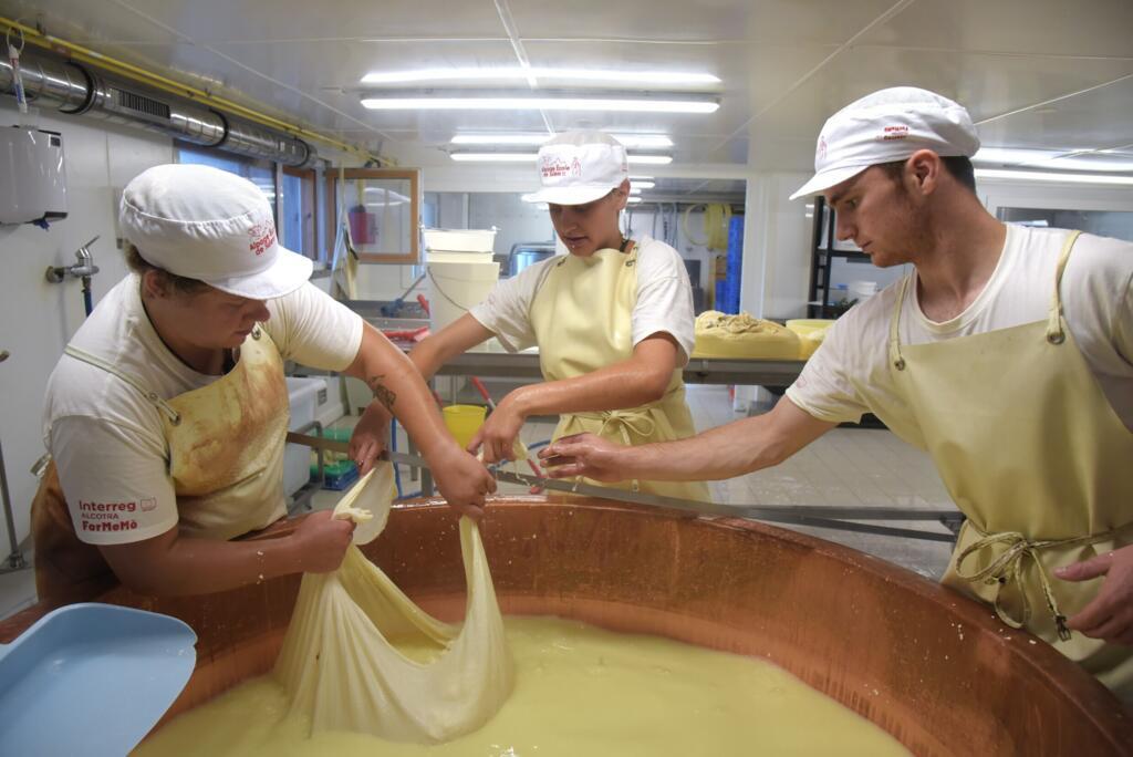 Pauline, la fromagère-monitrice, Noura et Corentin rassemblent le caillé du lait dans une toile qui servira à fabriquer des abondances.