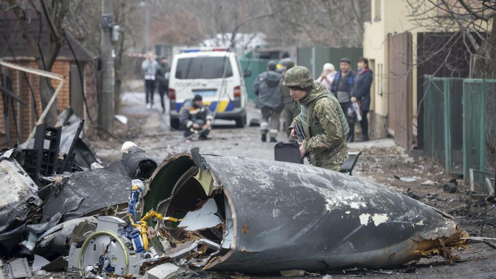 Un soldat de l'armée ukrainienne inspecte des fragments d'un avion abattu à Kiev, en Ukraine, le vendredi 25 février 2022.