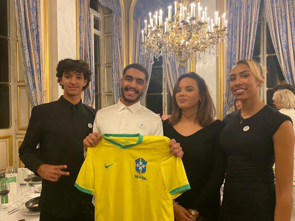 Walid segura camisa da Seleção em meio a grupo de jovens franceses que foram ao Brasil em 2022. Cinthia (direita) agora é treinadora de futebol de outras meninas na Sport dans la Ville.