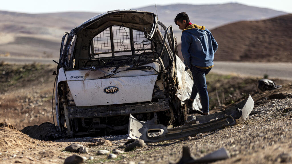 A man inspects a damaged car that hit by Turkish airstrikes near the village of Taql Baql, in Hasakeh province, Syria, Sunday, Nov. 20, 2022.