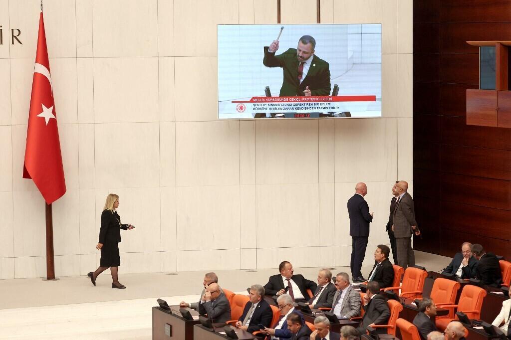 Lawmaker Burak Erbay (on screen) destroys his mobile phone in protest at Turkey's "disinformation law".